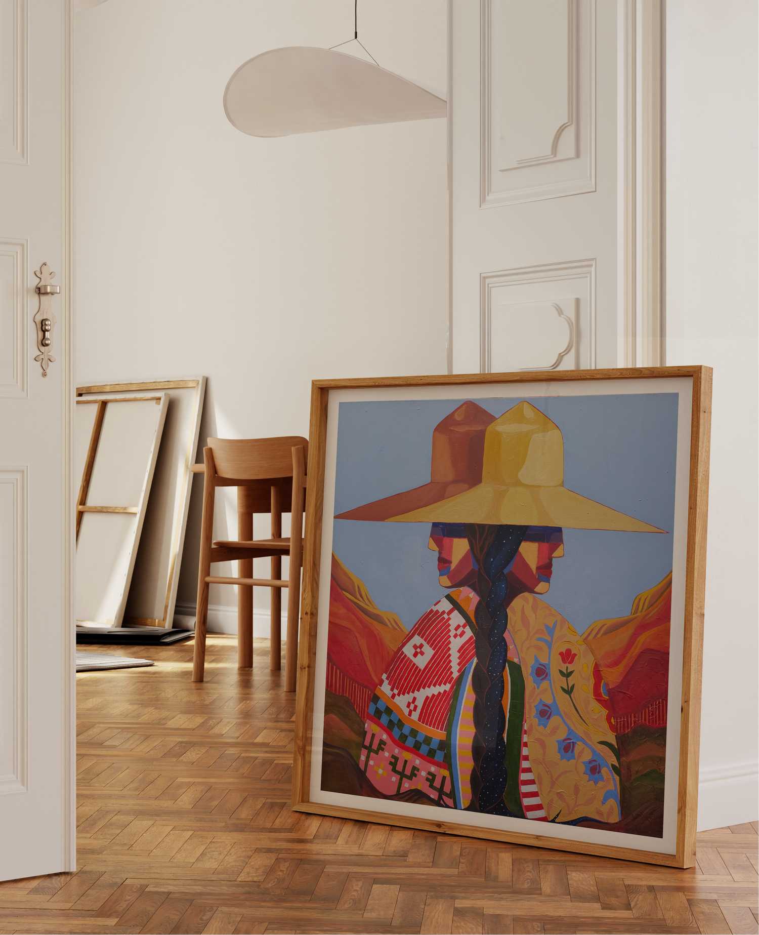 Framed artwork of a person wearing a colorful hat in a room with wooden floor and white walls.
