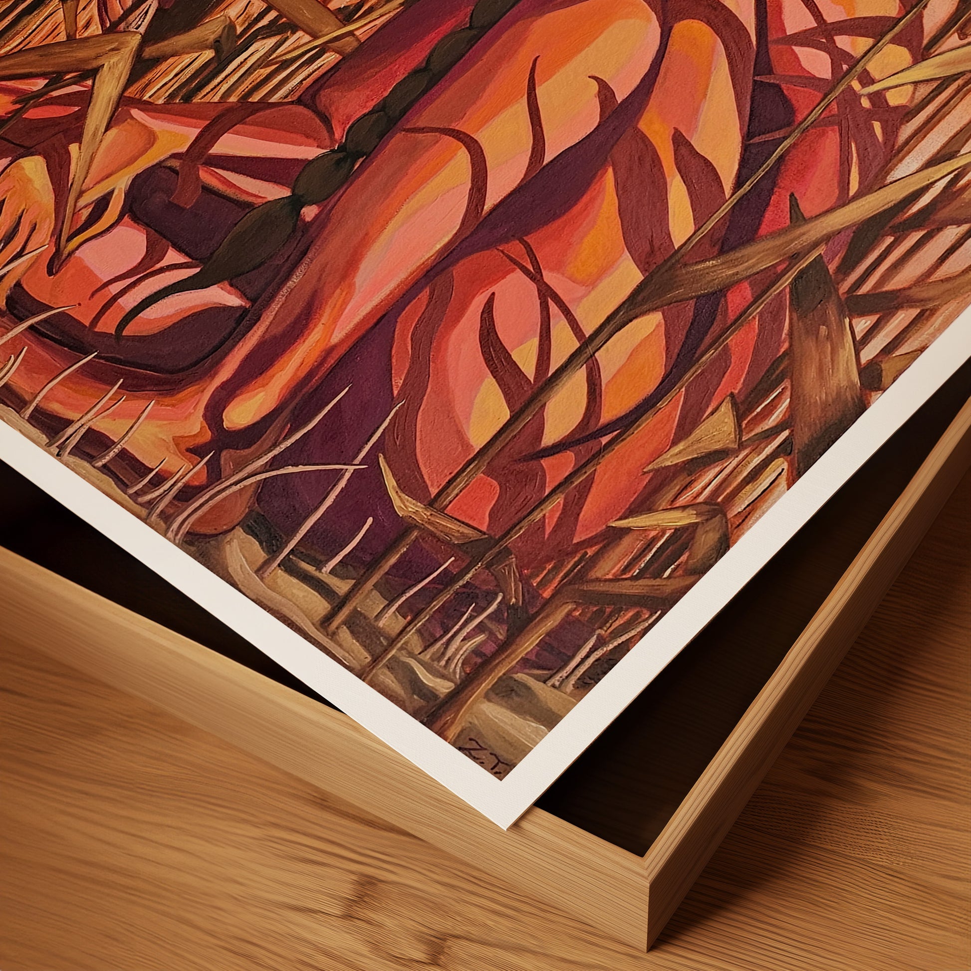 Framed abstract artwork with warm colors on a wooden surface